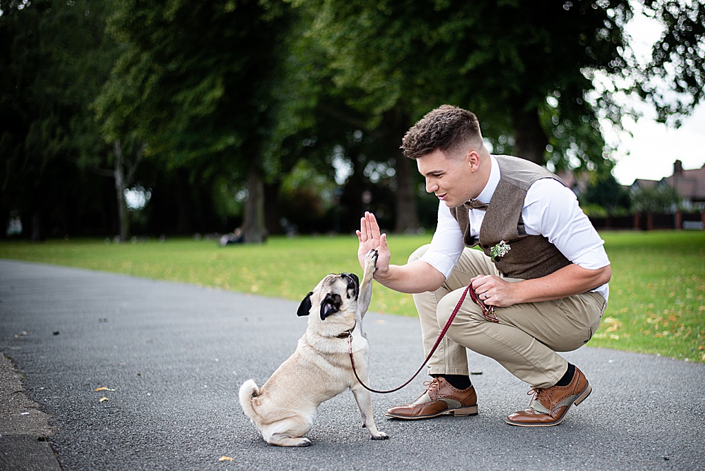 groom in suit with his small dog by derby and Nottingham wedding photographer