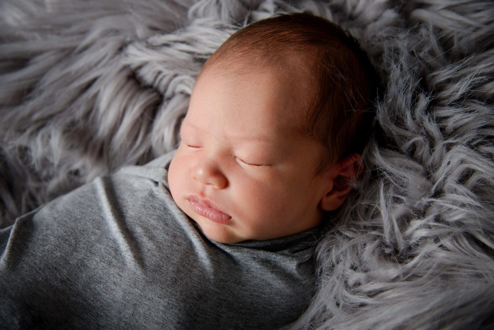 newborn baby boy swaddled in grey and photographed by NEWBORN PHOTOGRAPHER IN MANSFIELD, NOTTINGHAM