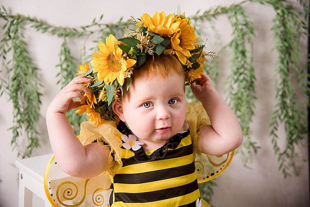 cute little girl in bee outfit with a big sunflower halo on her head