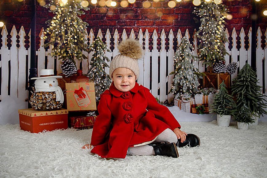 cute little girl on christmas backdrop with red coat on