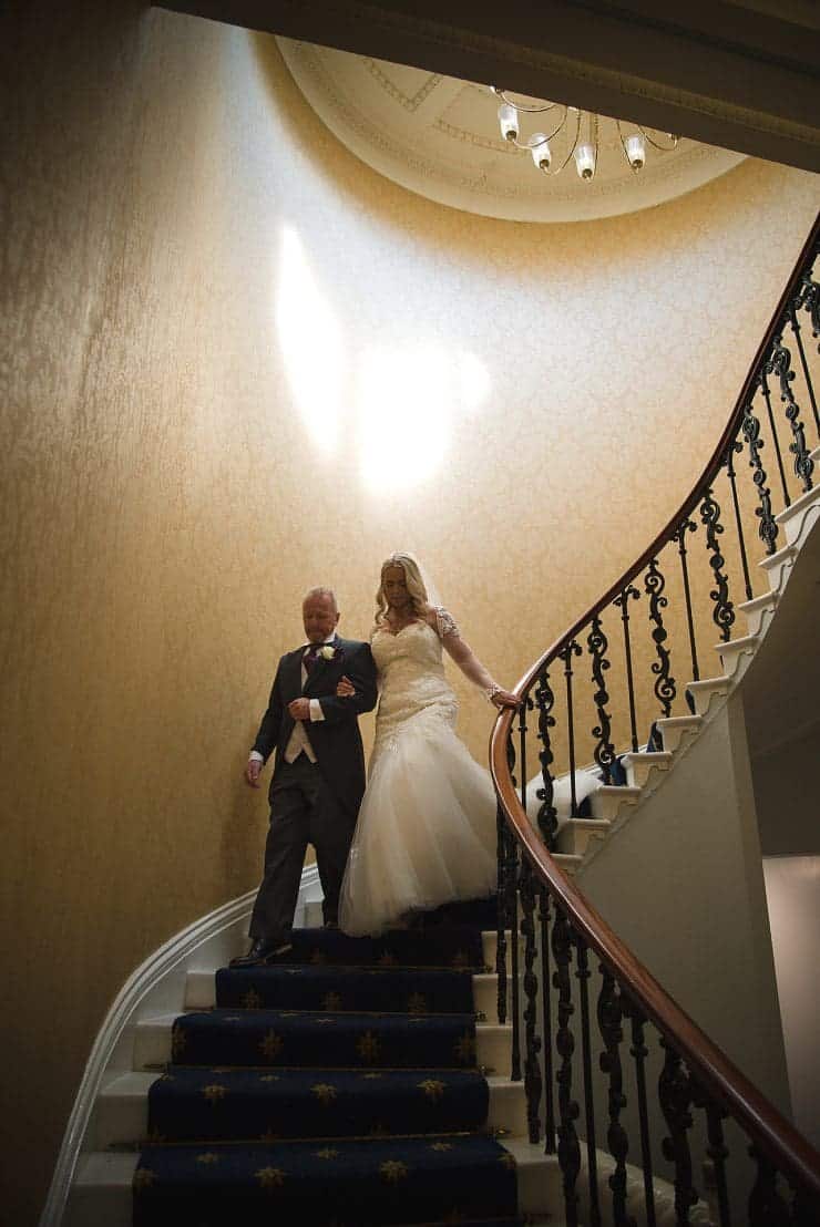 the bride walks down grand stair entrance with her father at eastwood hall in nottingham, photo