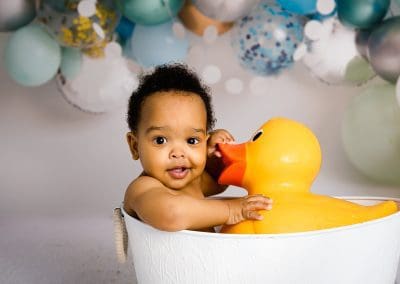 boy in the tub with a duck at his cake smash photography session in Mansfield Nottingham at Rachael Phillips Photography studio.