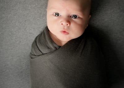 Bradley 6 weeks old baby boy wide awake on a grey fabric