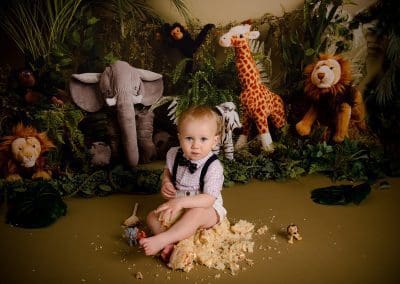 boy at his cake smash session, sat on cake with a jungle theme