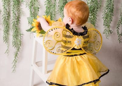 Harper dressed in a little bee costume with a beautiful halo on her head during her cake smash session with Rachael phillips Photography