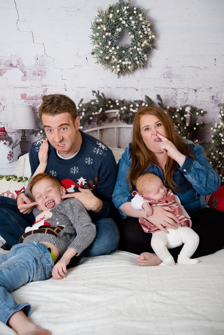 my crazy family at a christmas session reading a book on a bed pulling funny faces