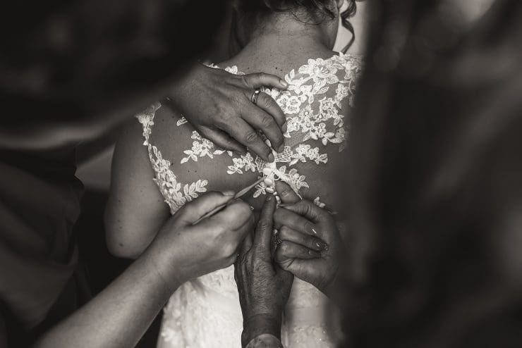 black and white photo of a bride getting her dress on