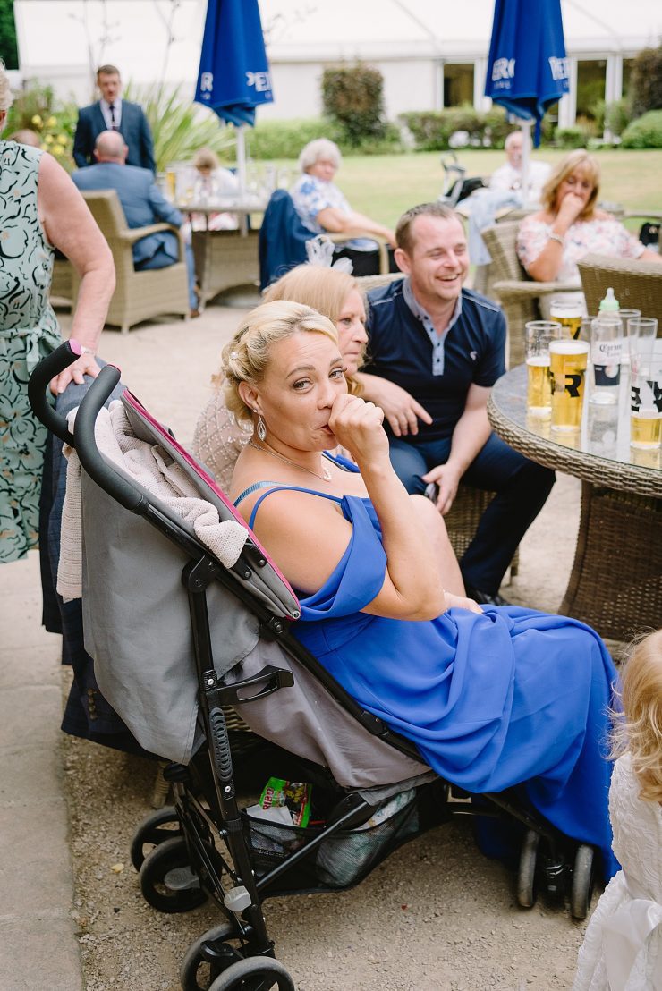 comical photo of a bridesmaid sucking her thumb sat in a pushchair