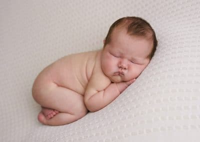 Newborn baby girl posing on his tummy on a blue blanket