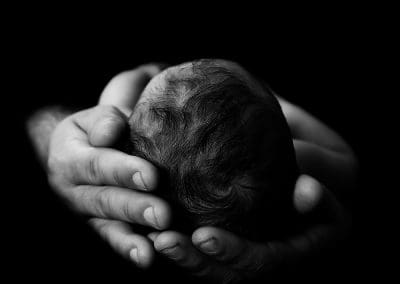 close up newborn baby head photo, in daddy's hands