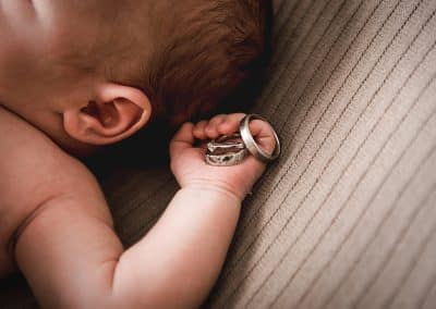 newborn baby close up of hands holding parents wedding rings