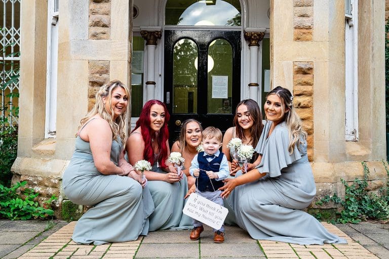 Bride with bridesmaids sitting with small pageboy on the steps by nottingham wedding photographer Derby Wedding Photographer