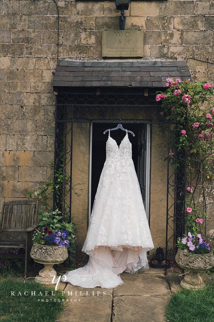 Brides wedding dress hanging up from the front door canopy of there home.