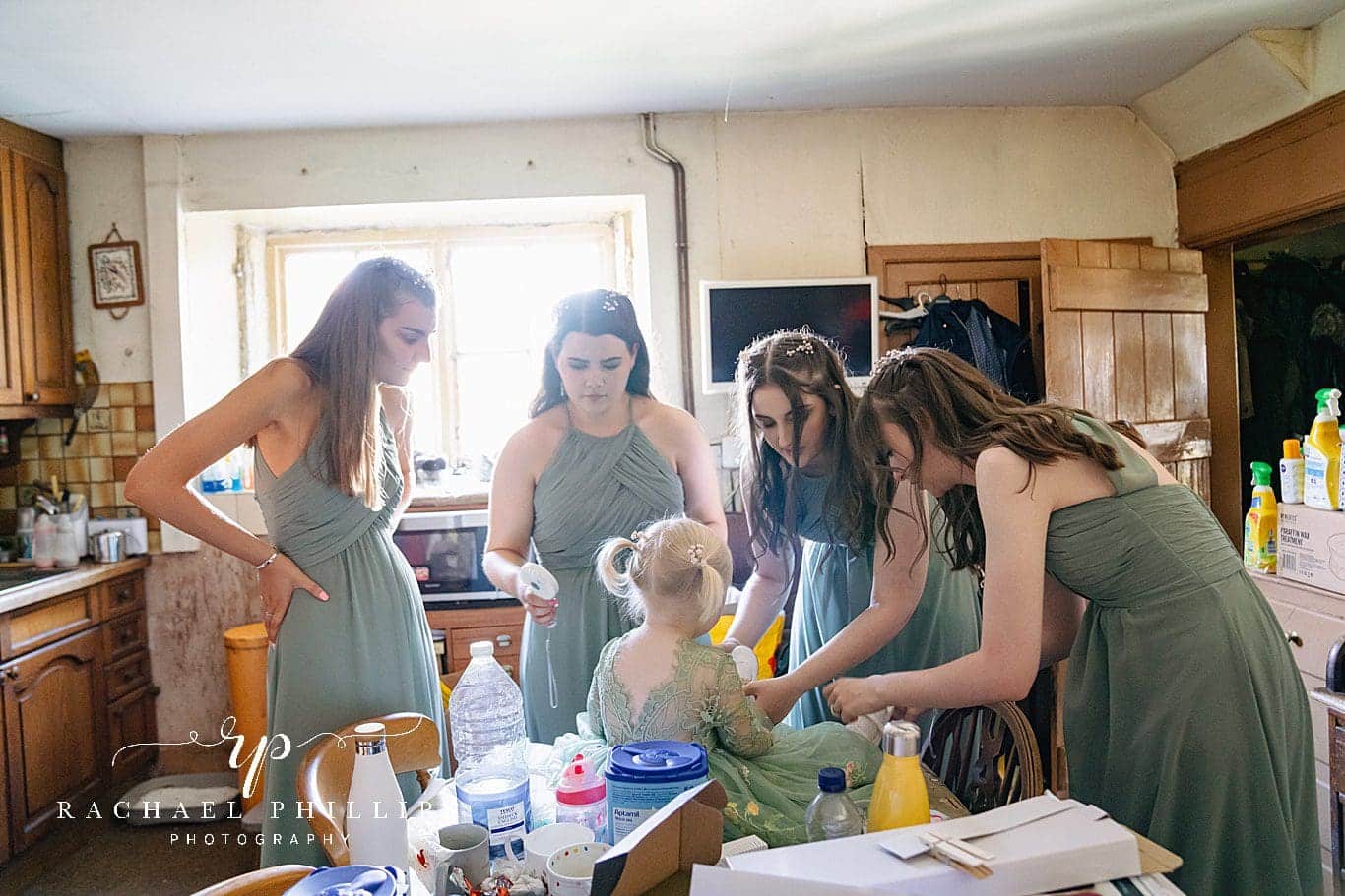 bridesmaids all in the kitchen helping the flower girl get ready