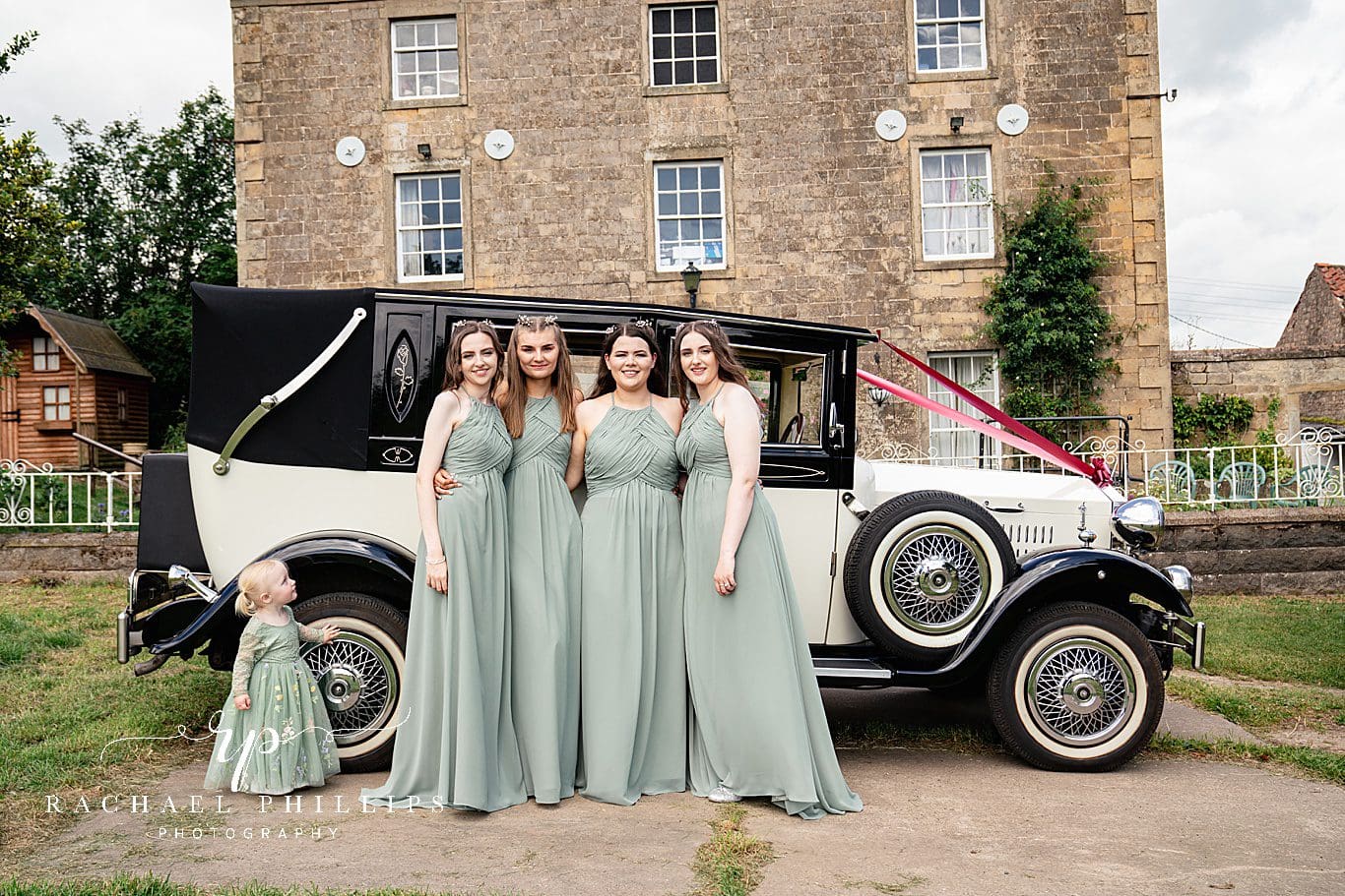 bridesmaids stood outside the family farm house in Mansfield, in front of a beautiful wedding car.