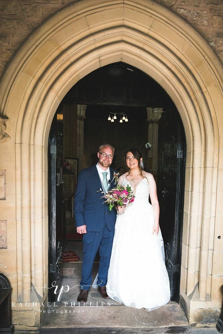 the bride and groom stood in the arch door way of the church in Mansfield