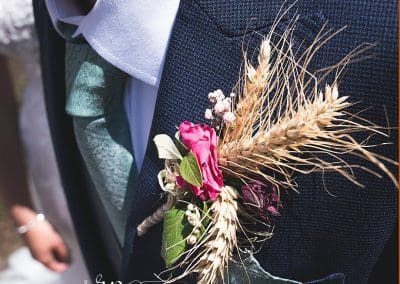 close up of the grooms button hole. its got some lovely flowers and wheat giving it a rustic farmers vibe.