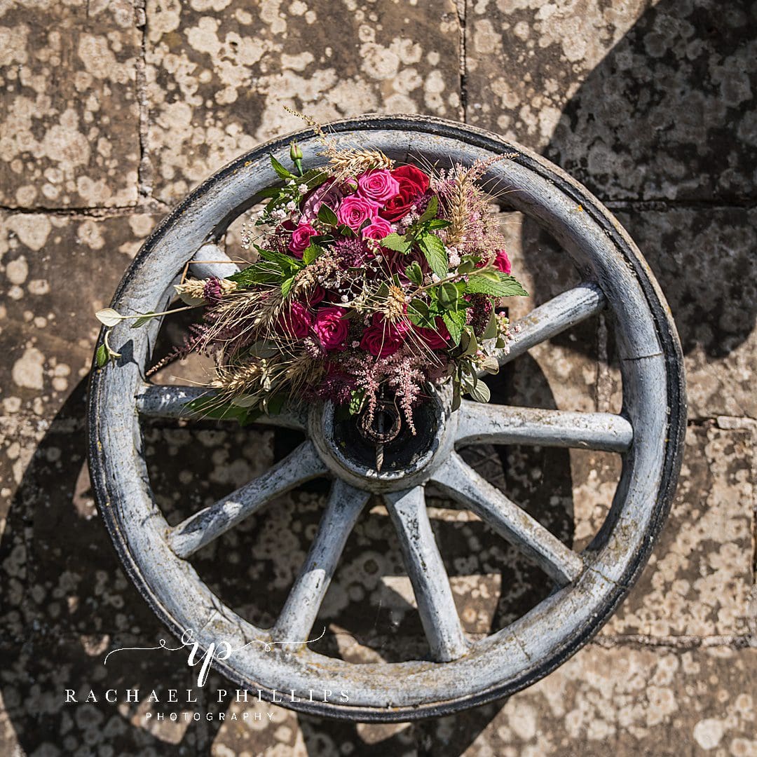 the brides flowers perched on an old wooden wagon wheel