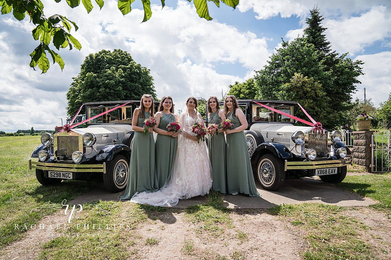 beautiful photo of the bride with her bridesmaids, they are stood in front of two lovely wedding cars outside there farm house