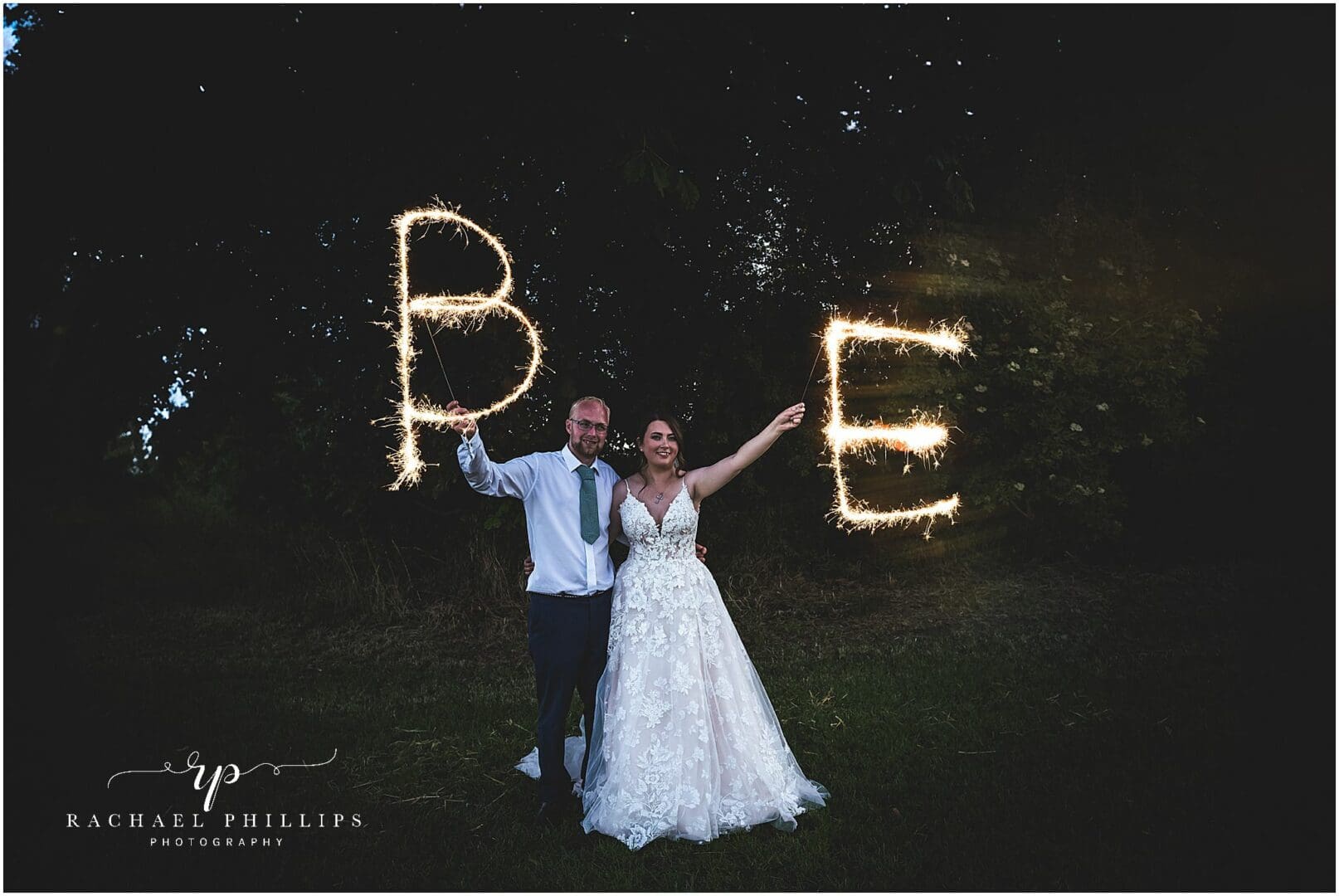 bride and groom standing nice and close as they write their initials with sparklers on their wedding day