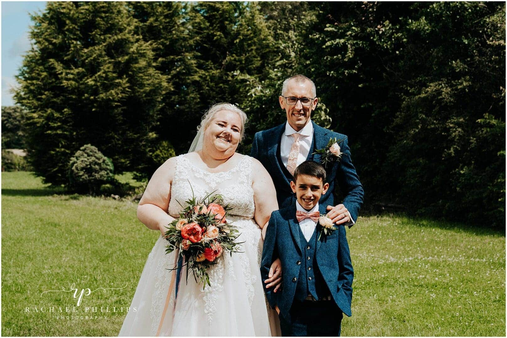 beautiful family photo of the bride and groom with their son on there wedding day.
