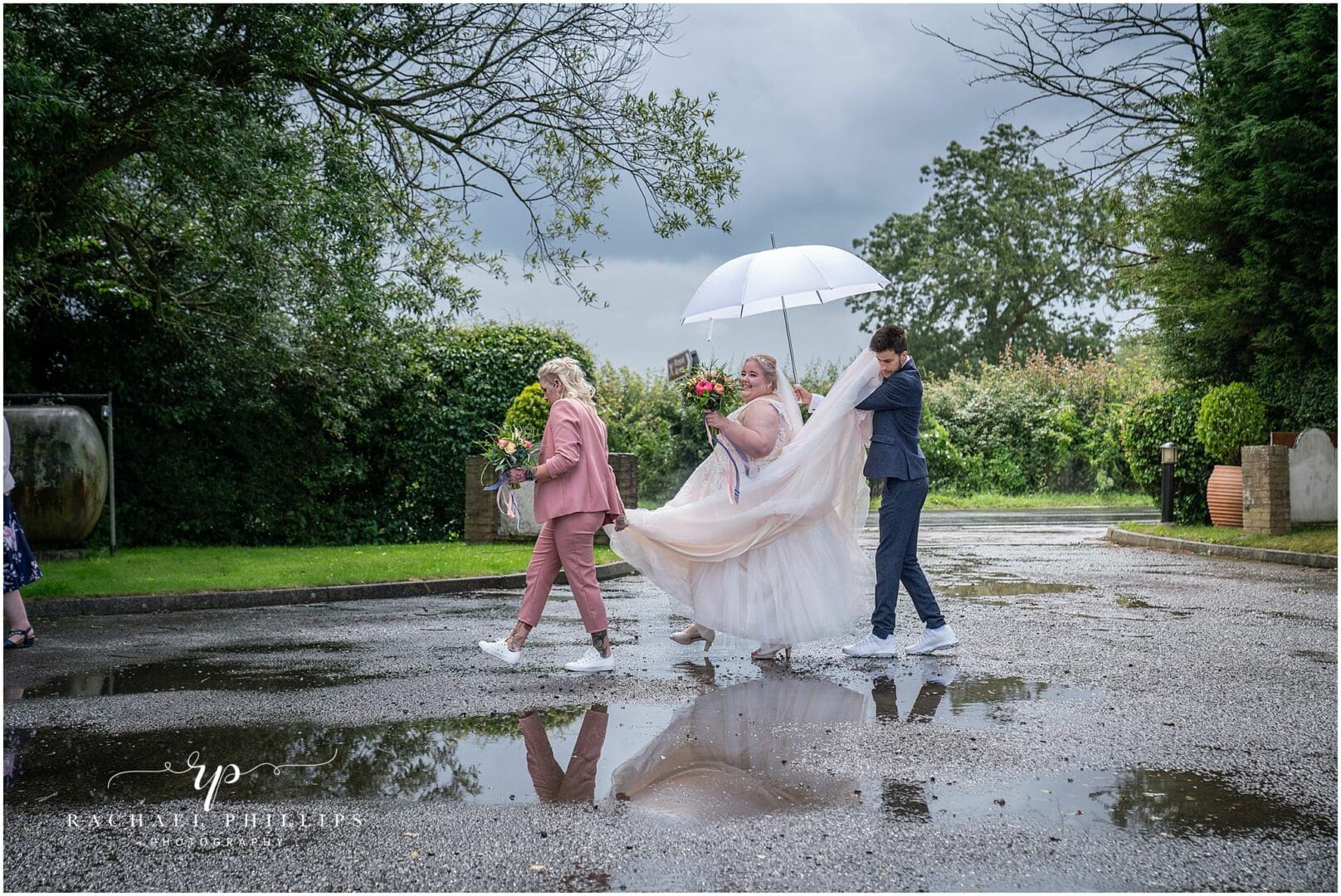 bride is being helped to her ceromony by her nephew and best friend, one is holding an umbrella as we had lots of rain and one is helping with her dress.