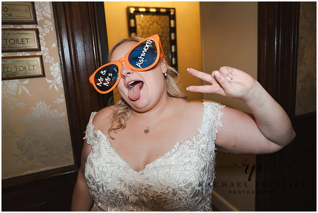 The bride is being silly wearing over sized funny glasses on the wedding day at Alfreton Hall in Derby