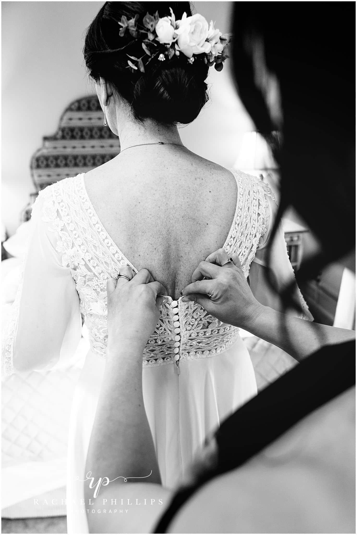 the back of the brides dress as shes helped to get ready, photo in black and white
