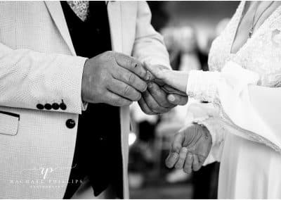 bride and groom exchange rings during the ceremony, its a close-up photo and in black and white