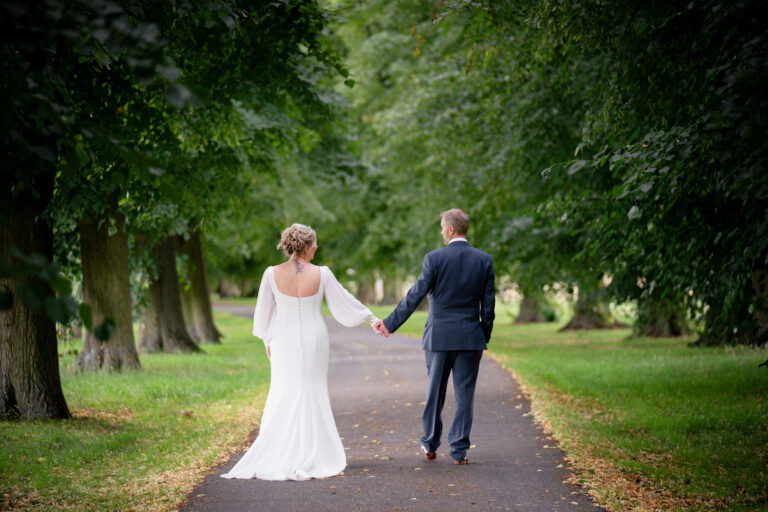 Bride and groom walking in a park.