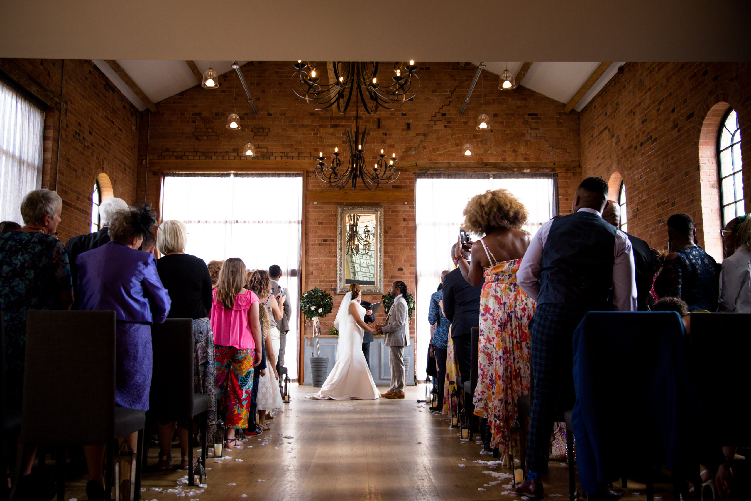 Wedding ceremony in brick chapel with guests seated.