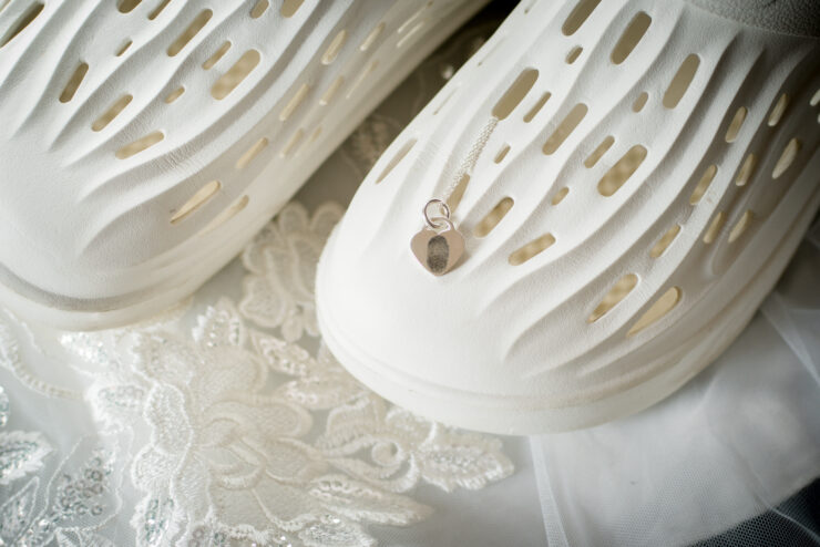 White clogs with heart pendant on lace fabric.