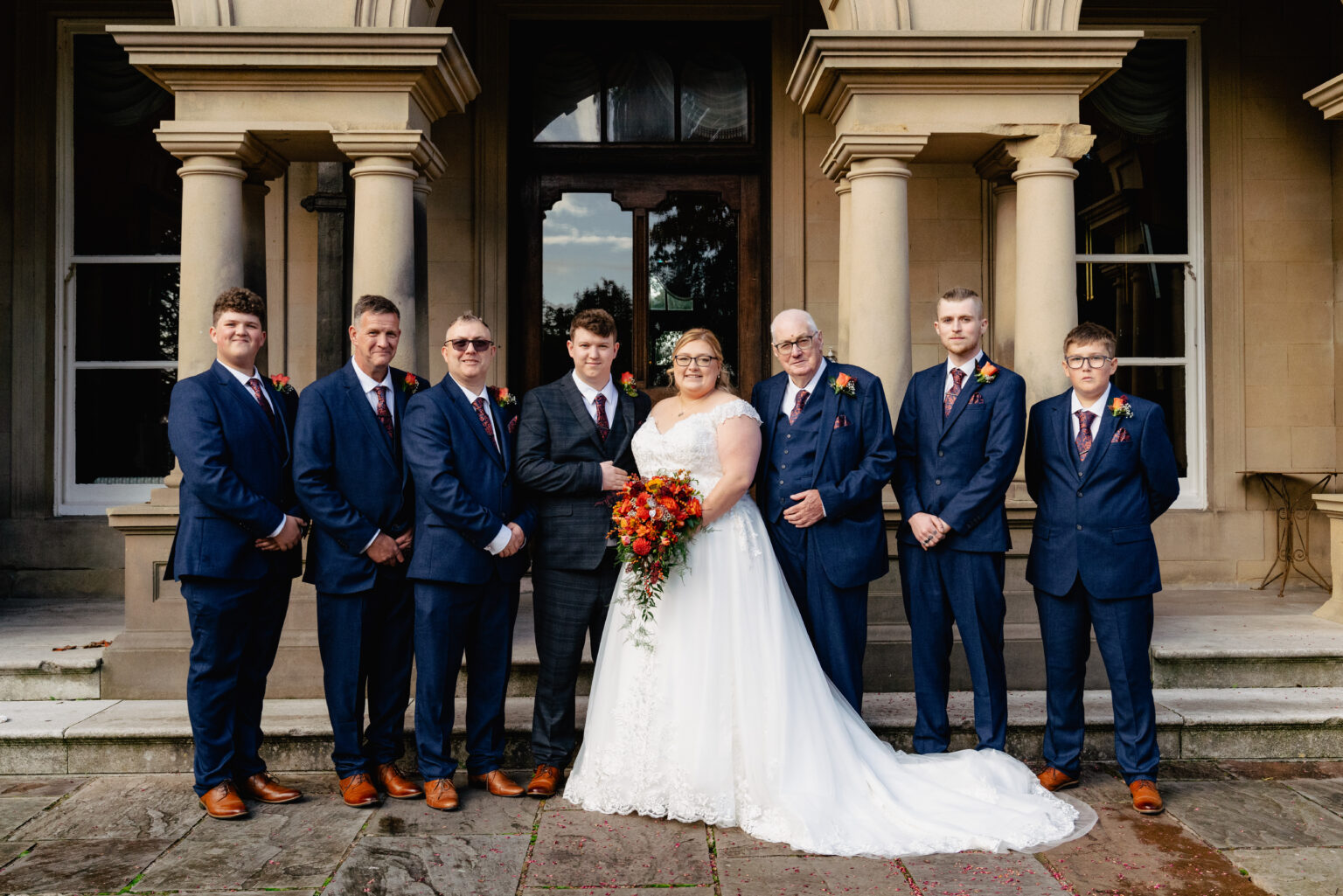 Bride and groom with groomsmen in blue suits.