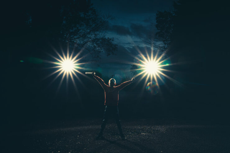 Person holding lights in dark outdoor setting
