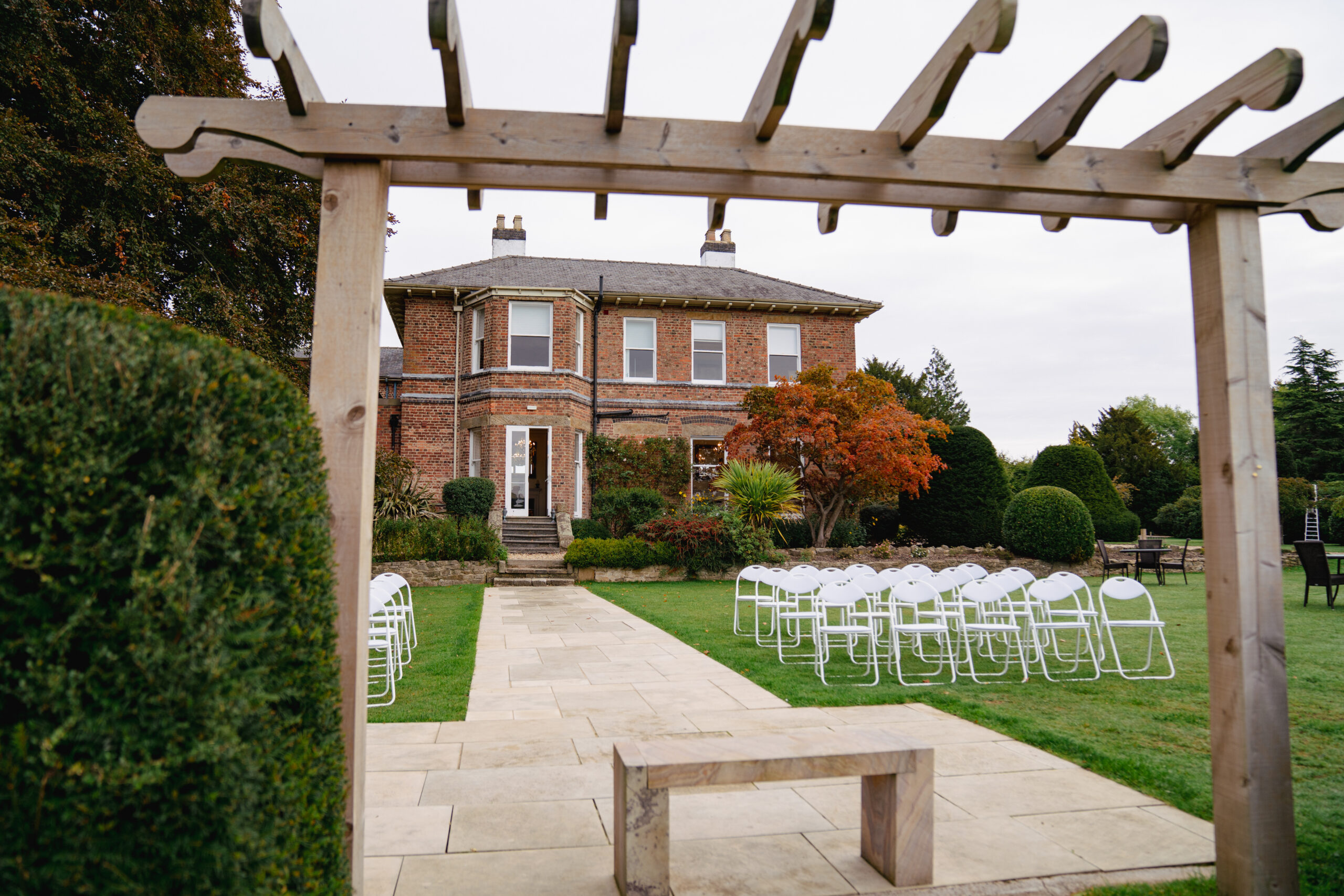 Outdoor garden wedding venue with chairs and archway.