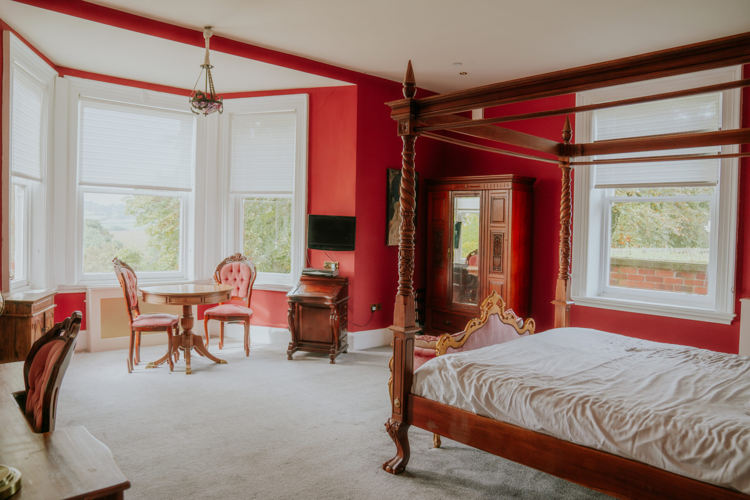 Spacious bedroom with red walls and antique furniture.