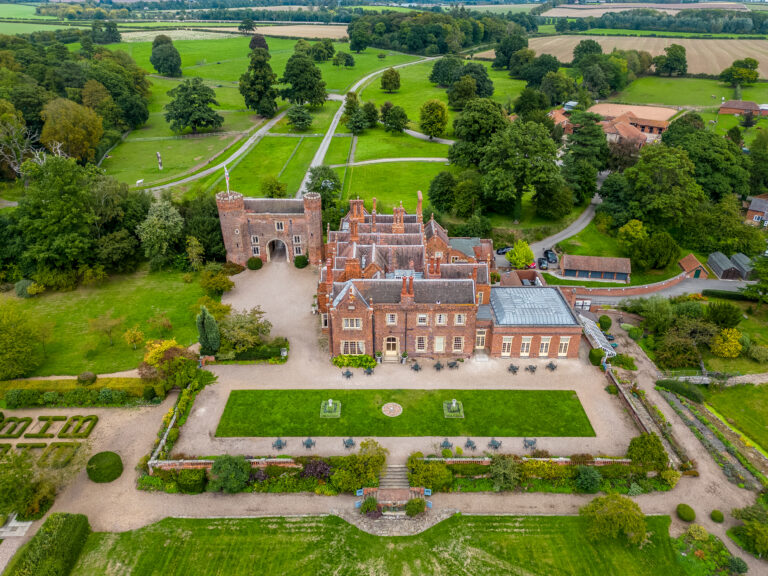 Aerial view of historic castle surrounded by gardens.