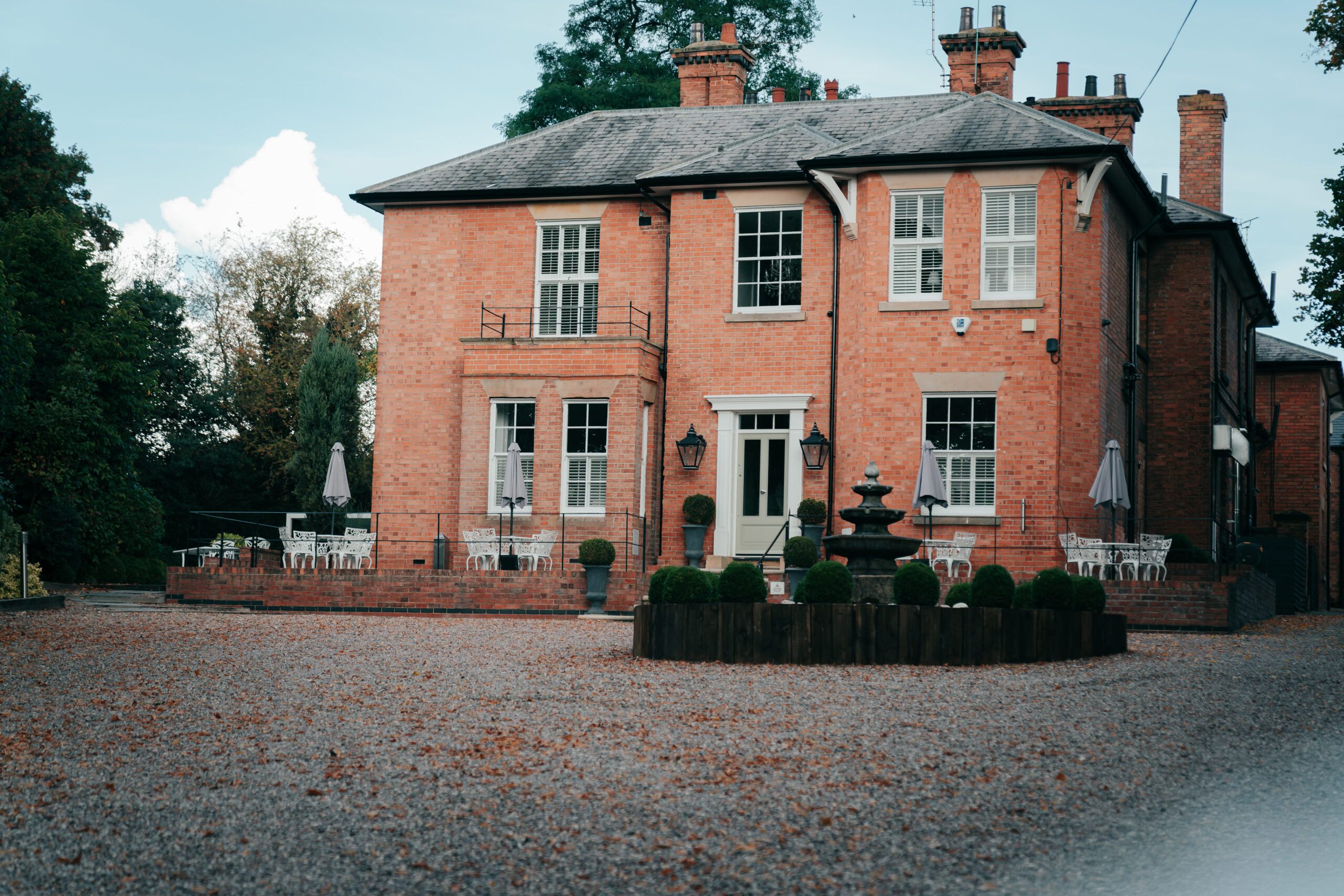 Historic red-brick house with garden fountain.