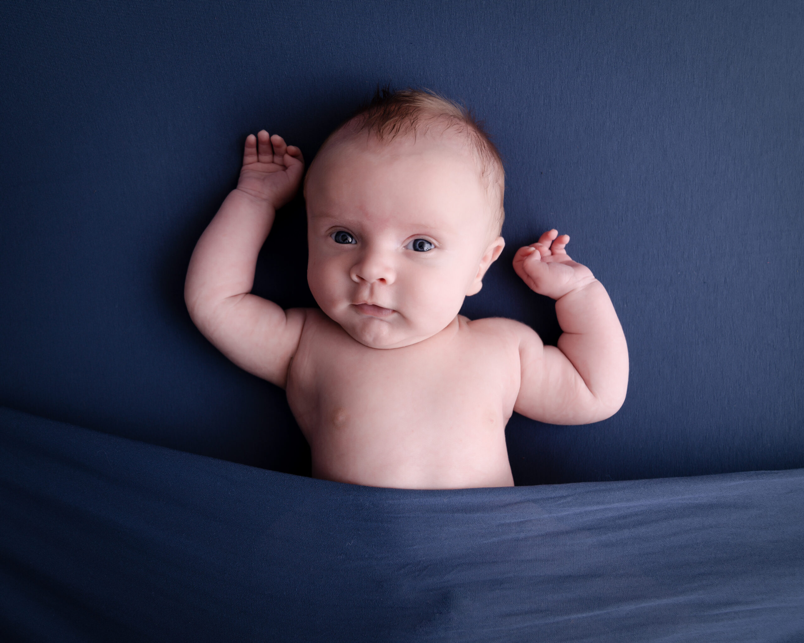 Baby lying on blue background.