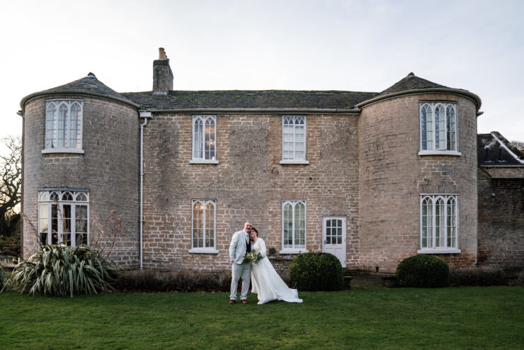 Bride and groom outside historic stone house.