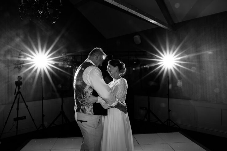 Couple dancing, illuminated by bright lights.