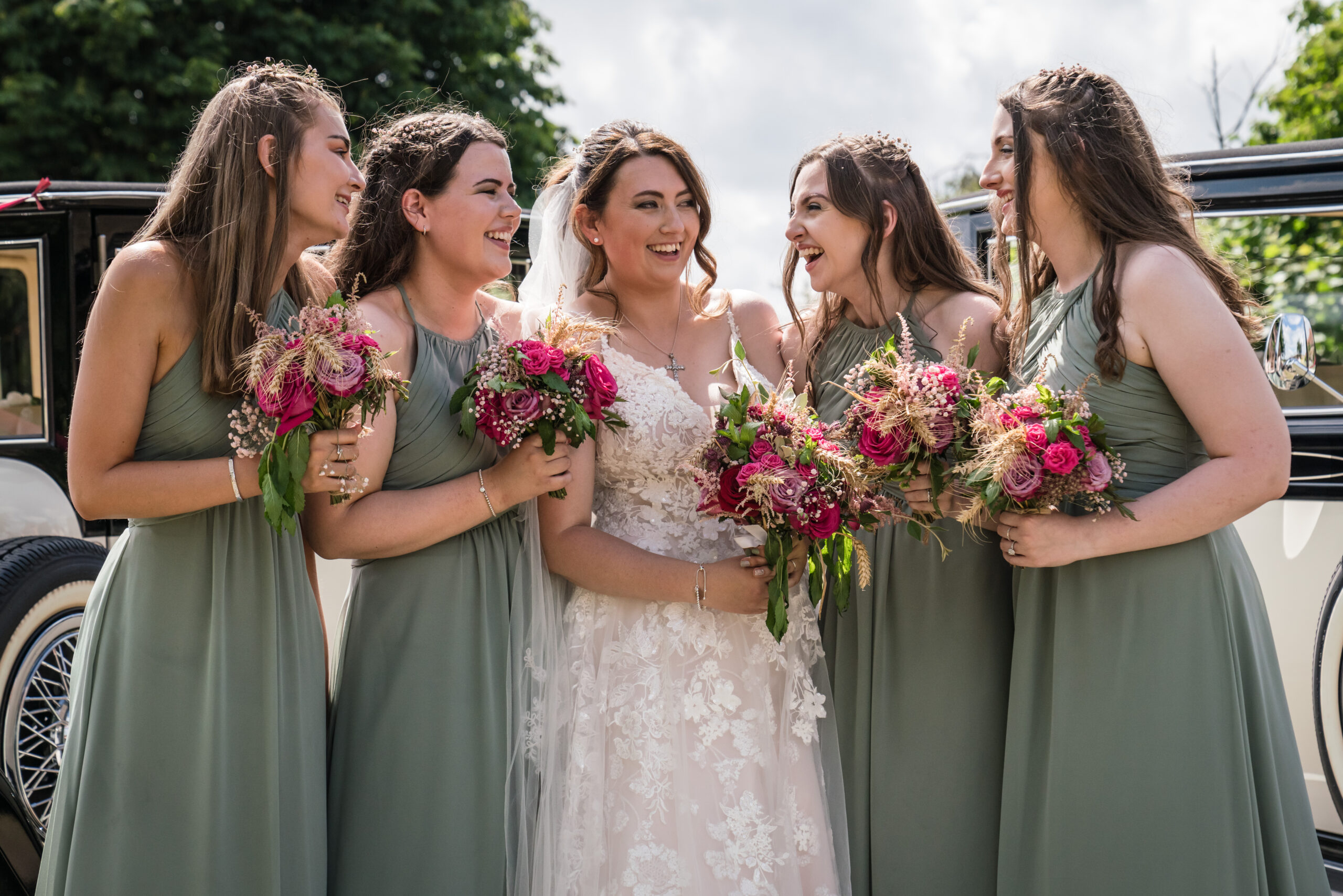 Bride with bridesmaids holding bouquets outdoors.