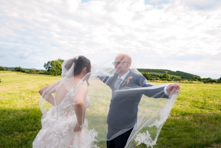 Bride and groom under veil in a field