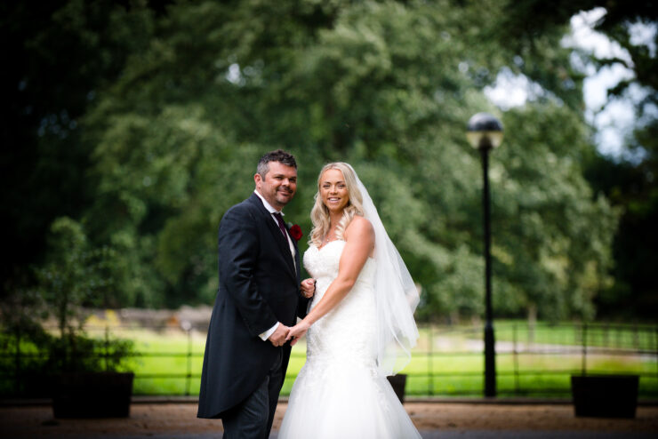 Bride and groom posing in park setting.