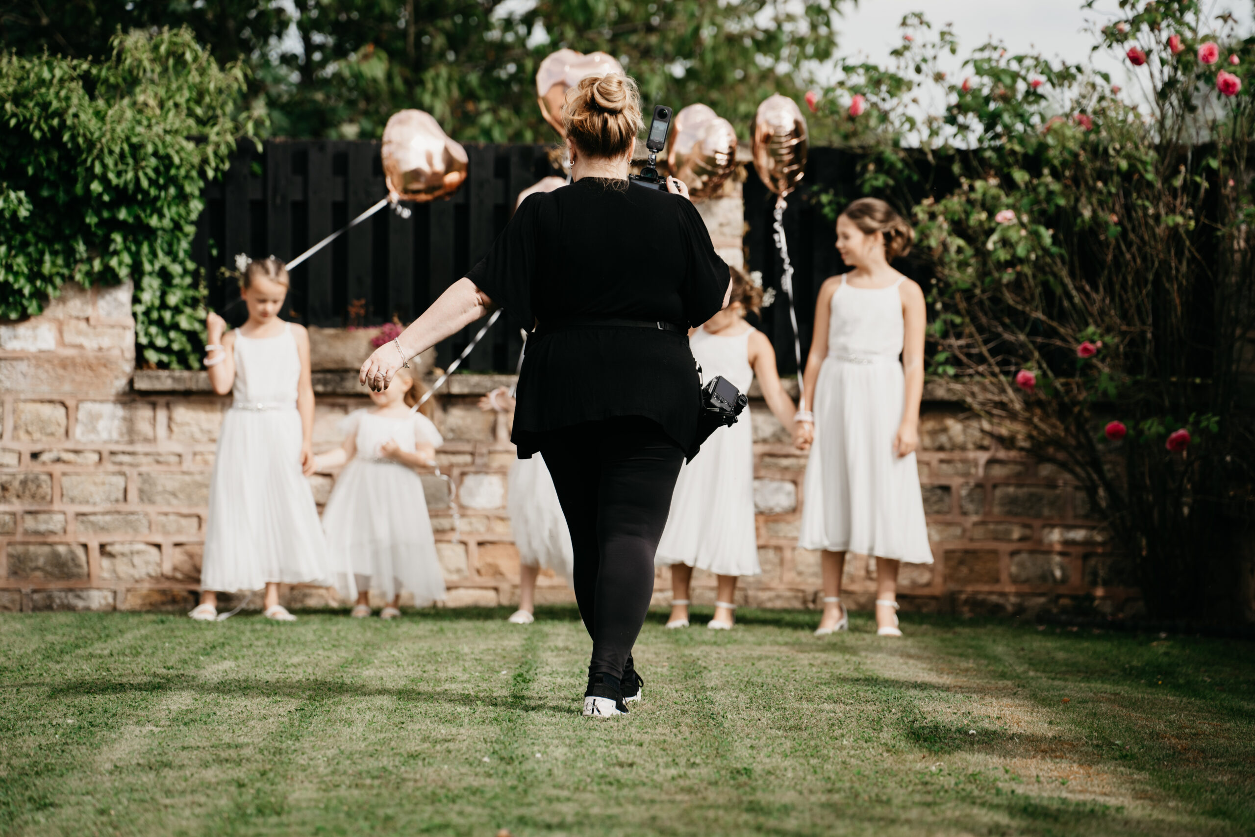 Photographer directing girls with balloons outdoors