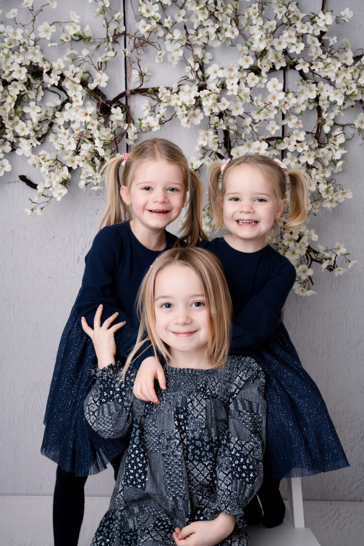 Three smiling girls with floral background.