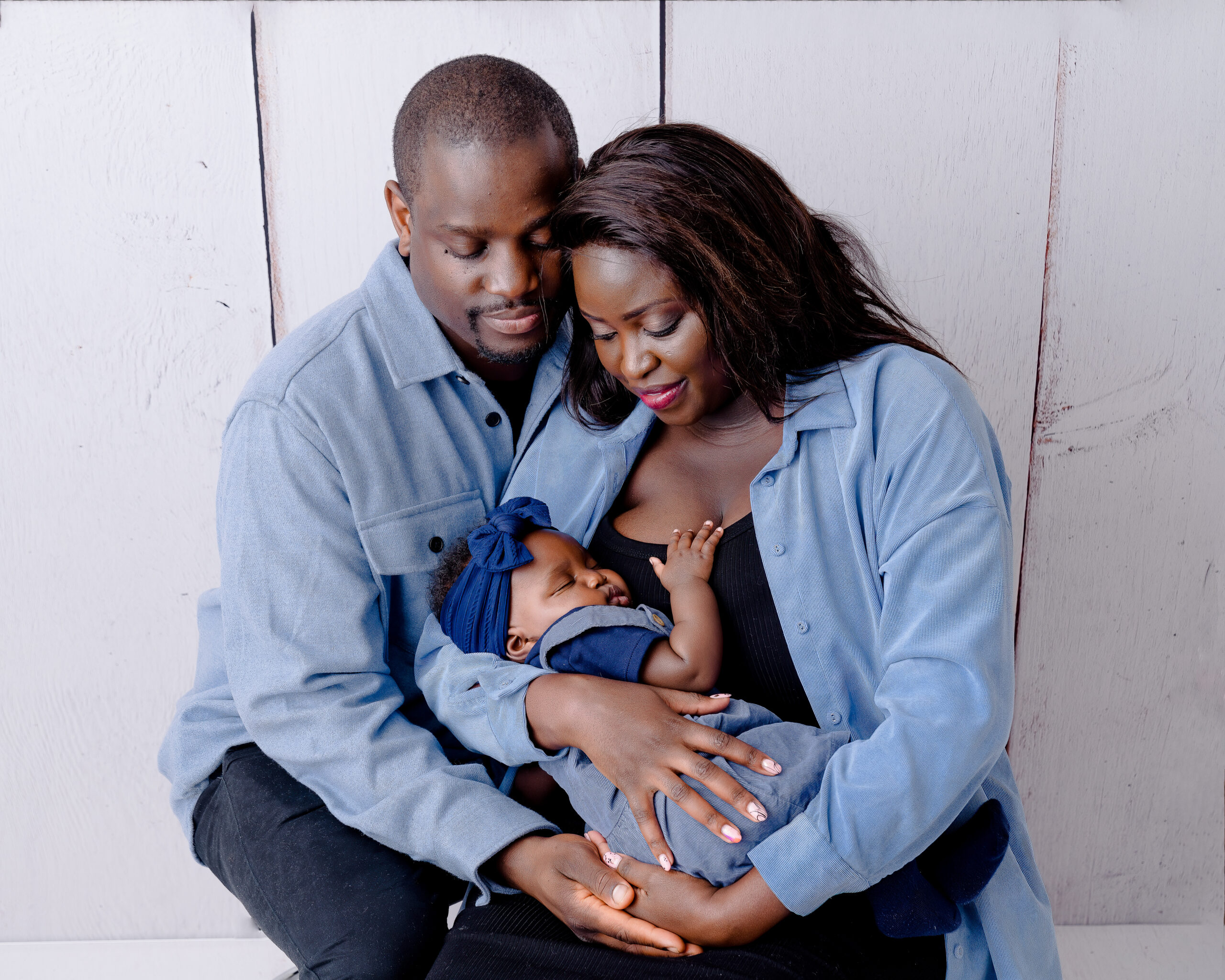 Happy family with newborn baby in blue clothing.