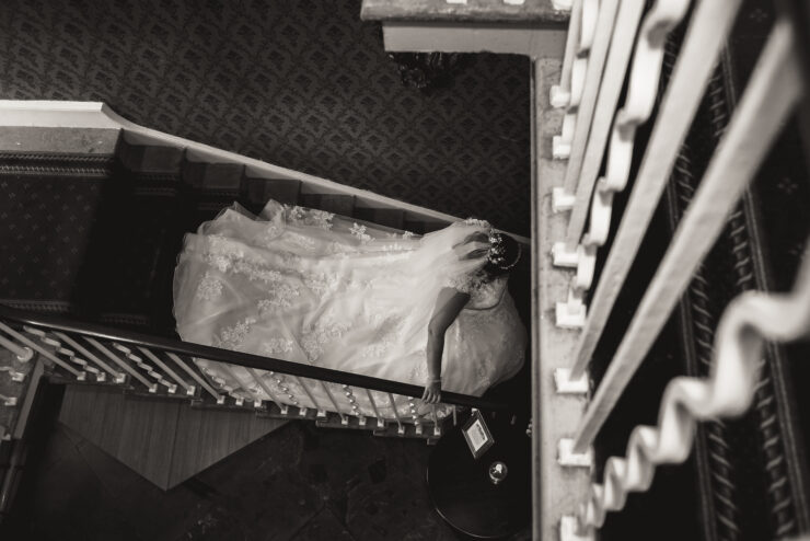 Bride descending staircase in elegant wedding gown.