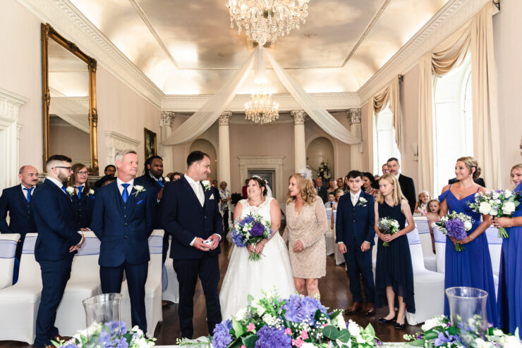 Elegant wedding ceremony in a grand hall with guests.