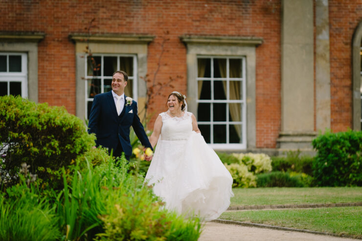 Smiling couple walking outdoors in wedding attire.